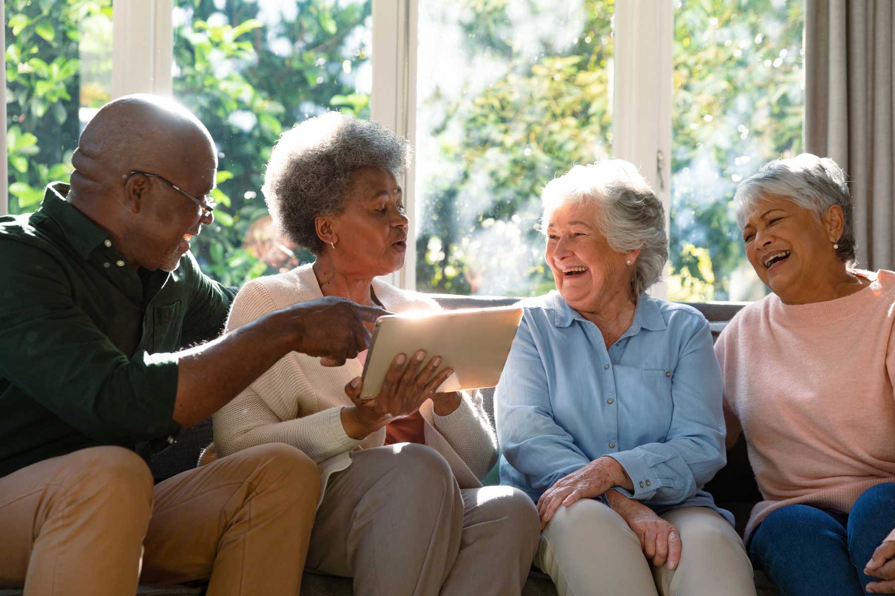 a group of seniors sitting on a couch looking at a tablet