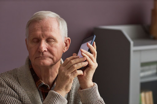 a senior man listening to something on his phone with his eyes closed